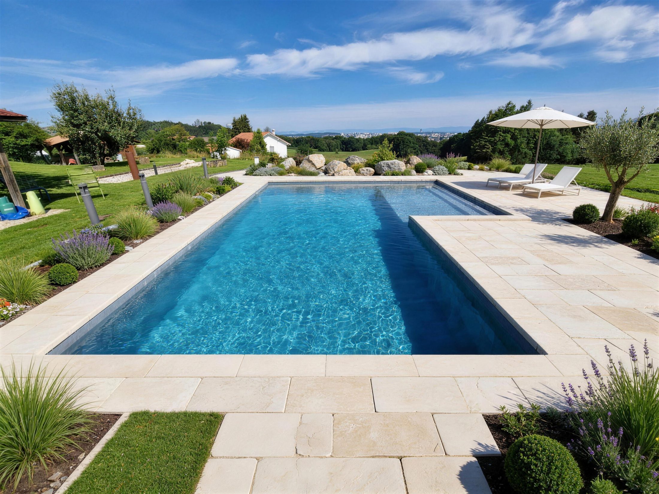 Piscine rectangulaire bordée d’une plage en pierre claire, au milieu d’un jardin fleuri