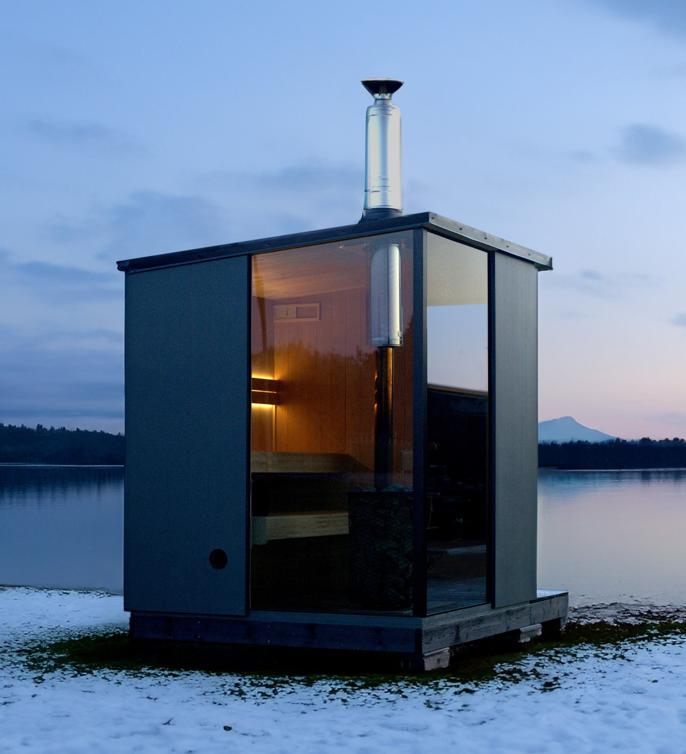 Sauna d’extérieur S4 éclairé au bord d’un lac enneigé, à la tombée du jour